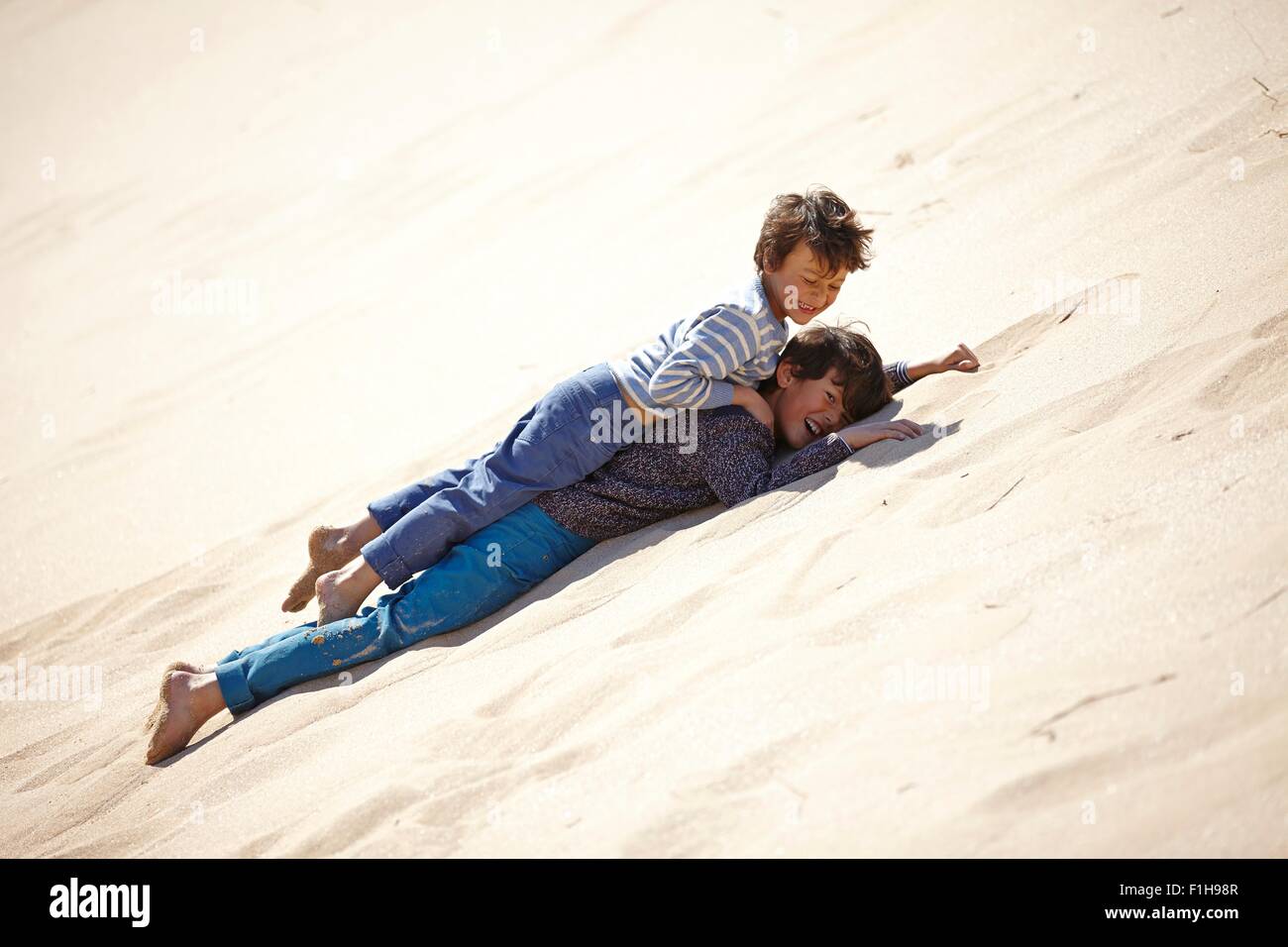 Deux jeunes garçons couchés sur la côte de sable, jouer Banque D'Images