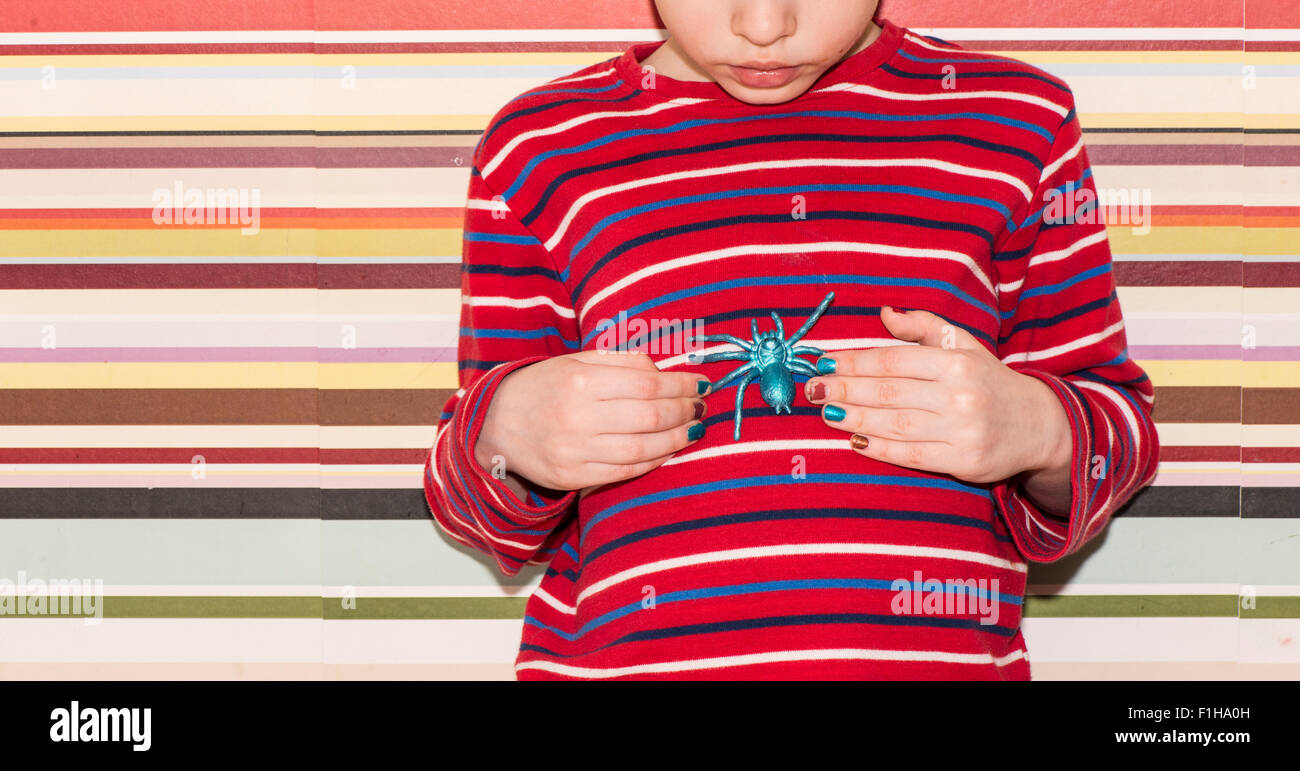 Little girl holding a toy plastique araignée dans ses mains. Image conceptuelle de l'enfance, la curiosité, la fantaisie et l'aventure. Banque D'Images