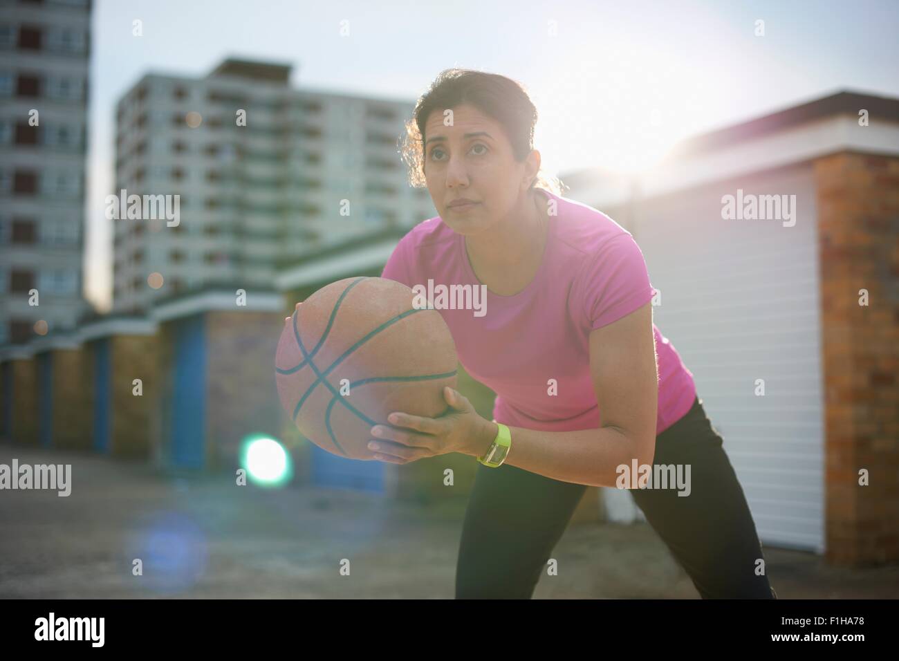 Femme mature la pratique de basket-ball au crépuscule Banque D'Images