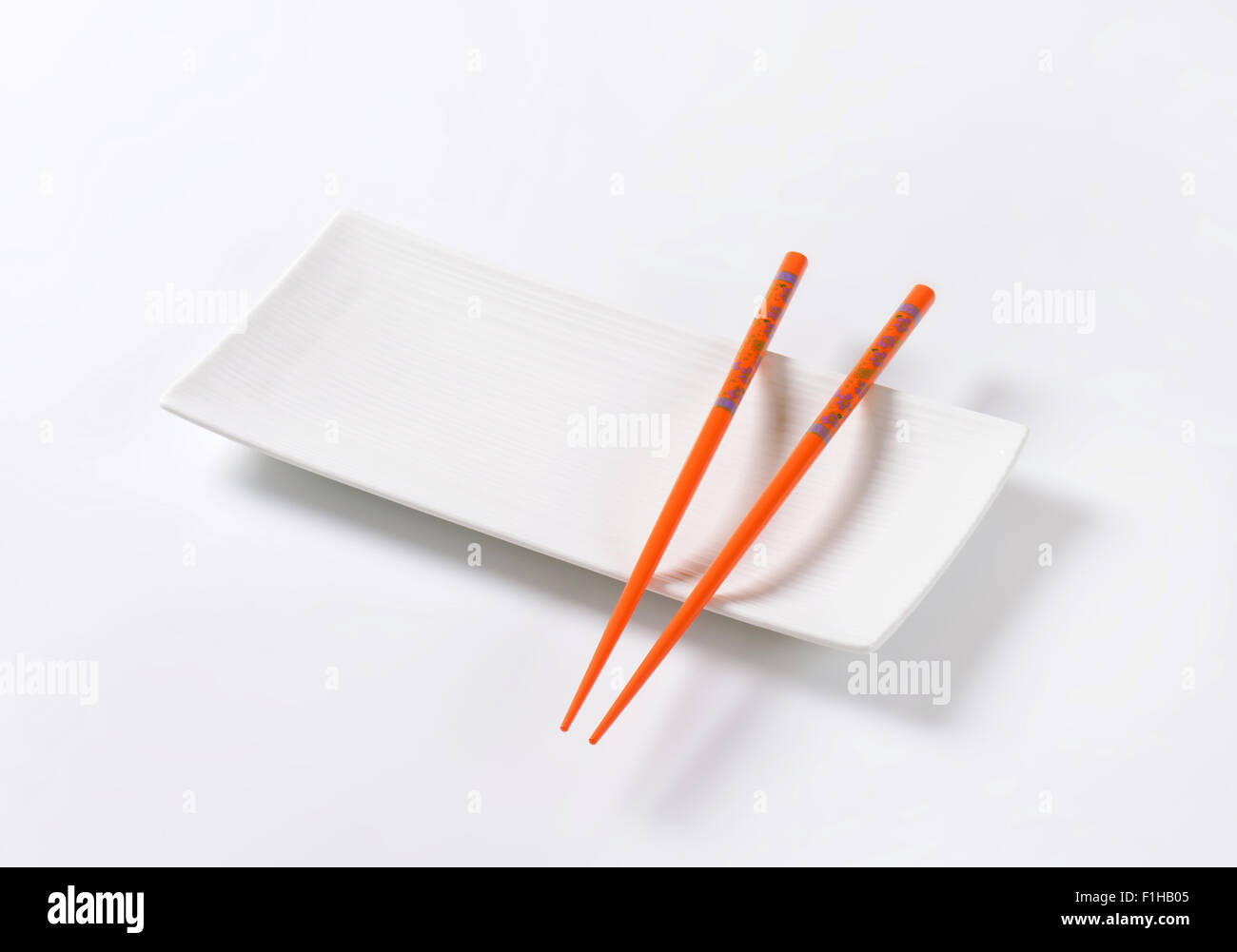 Paire de baguettes orange on white plate Banque D'Images