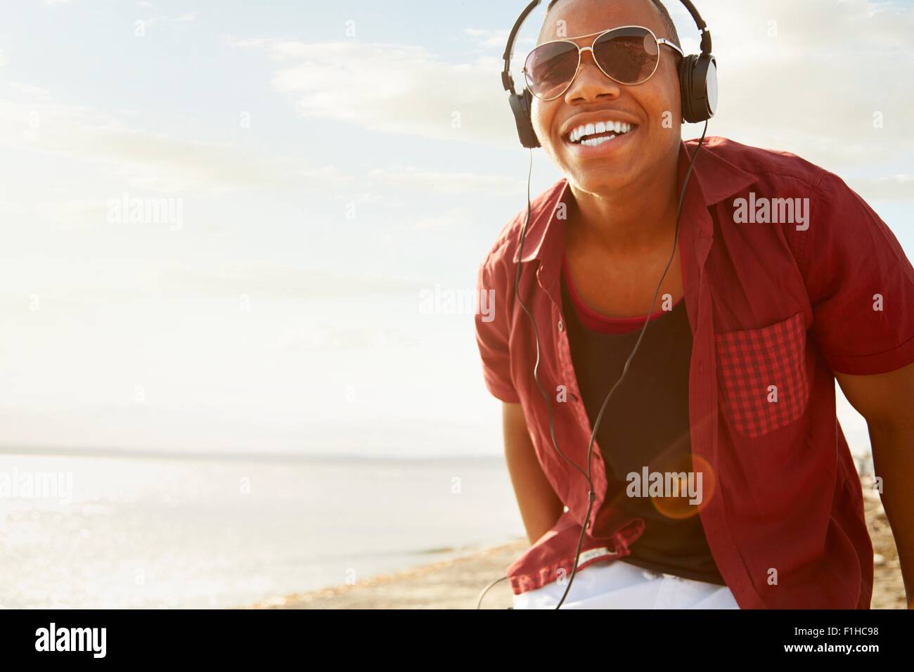 Jeune homme portant un casque et des lunettes de soleil, smiling at camera Banque D'Images