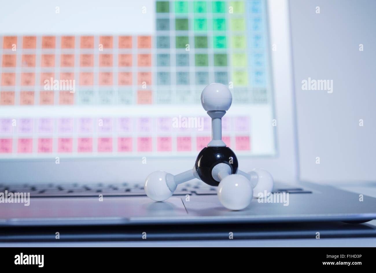 La recherche en chimie. Une balle et le bâton, molécule de méthane modèle sur un ordinateur portable affichant les éléments du tableau périodique Banque D'Images