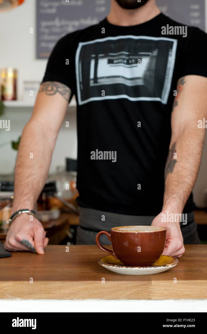 Cropped shot of cafe waiter serving tasse de café frais Banque D'Images