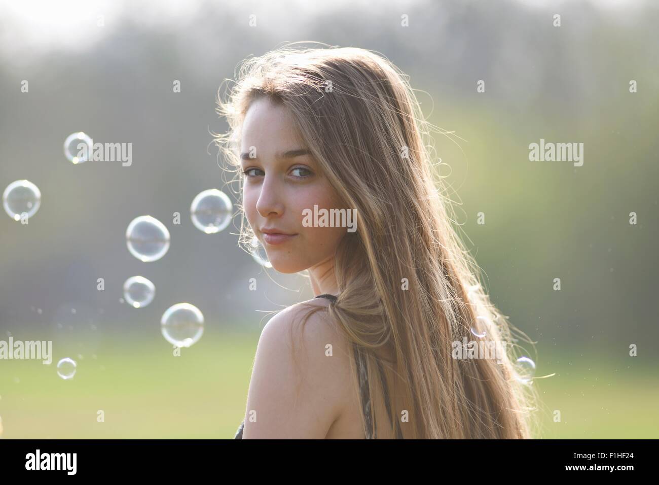 Portrait of teenage girl looking over her shoulder in park Banque D'Images