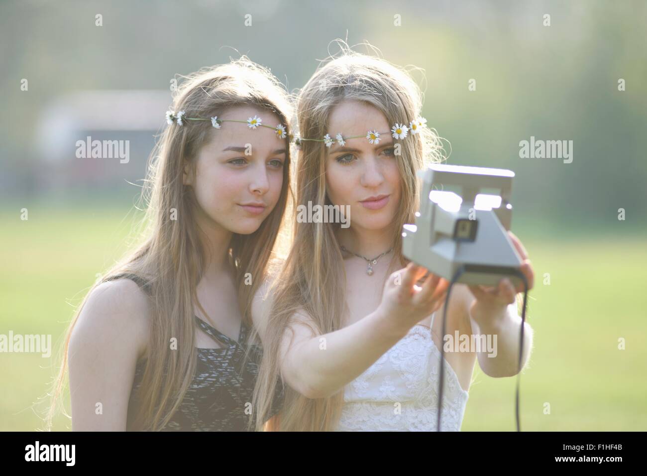 Deux adolescentes à park en tenant l'appareil photo instantané selfies Banque D'Images