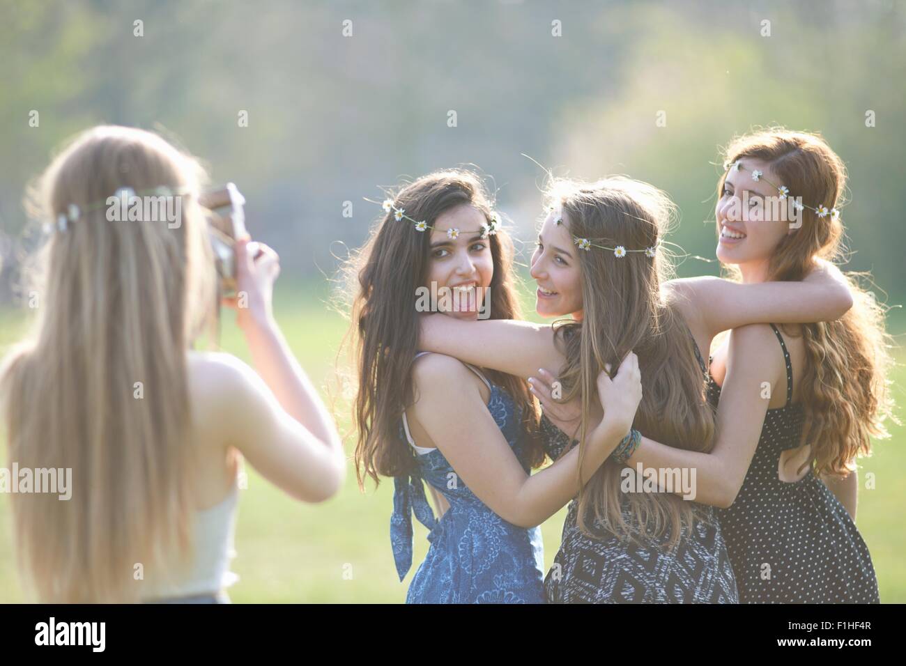 Teenage girl photographing trois amis à l'aide de la caméra dans park Banque D'Images