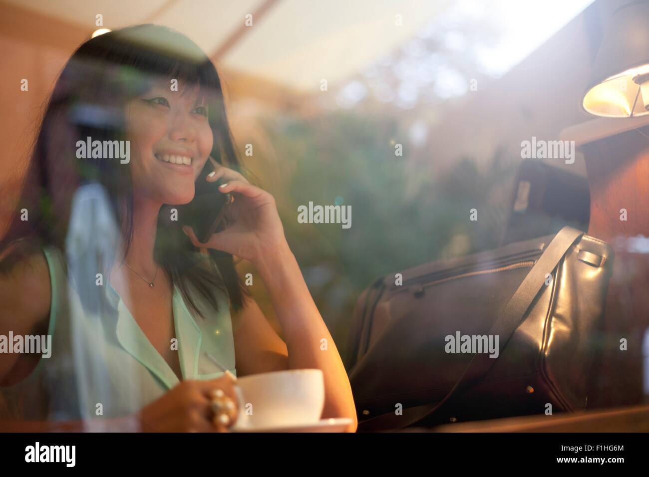 Jeune femme à boire le café dans un café, à l'aide de smartphone, Shanghai, Chine Banque D'Images