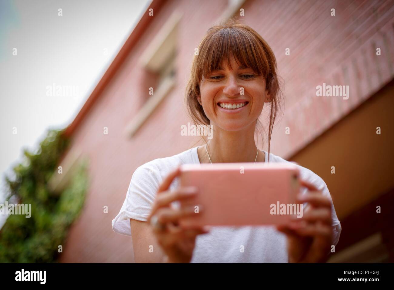 Faible et view of mid adult woman using smartphone, smiling Banque D'Images