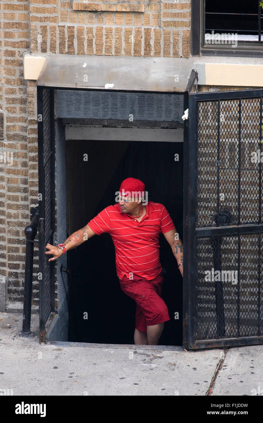 Membre de l'hispanique "Bloods' Street Gang vêtu de rouge secret, debout dans un tunnel d'accès d'un immeuble à appartements. Banque D'Images
