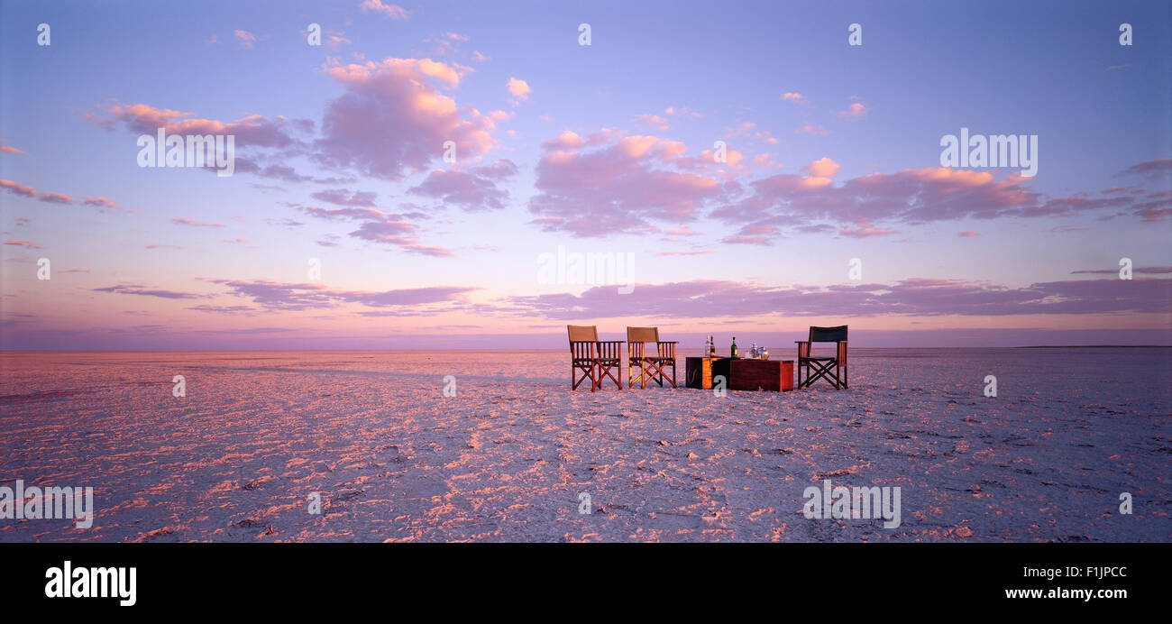 Table et chaises dans le désert au coucher du soleil Kubu Island, Botswana, Africa Banque D'Images