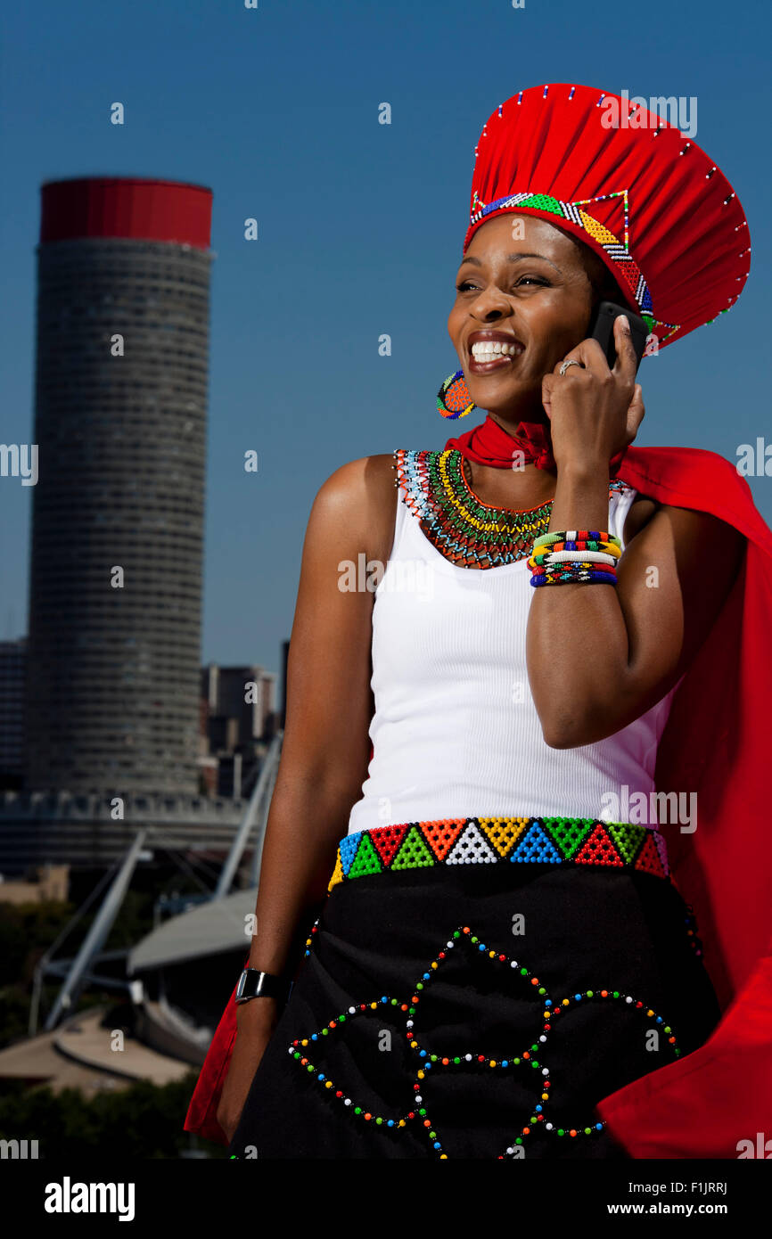 Habillé traditionnellement femme parle d'Afrique on cellphone with cityscape in background Banque D'Images