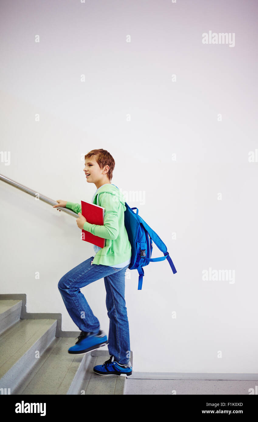 Pré-ado collégien avec sac à dos en montant les escaliers à l'école Banque D'Images