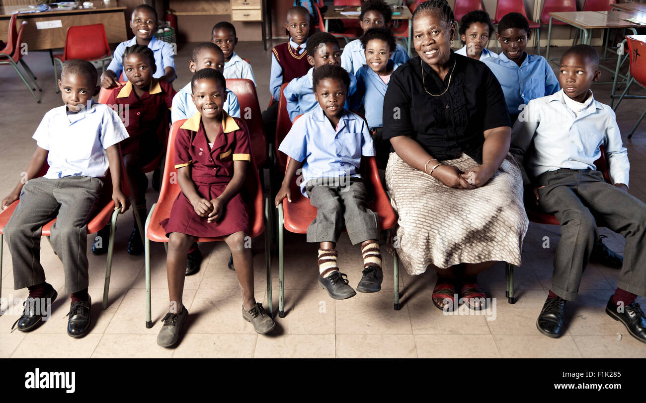 Femme africaine assis l'enseignant avec ses élèves, smiling at camera Banque D'Images