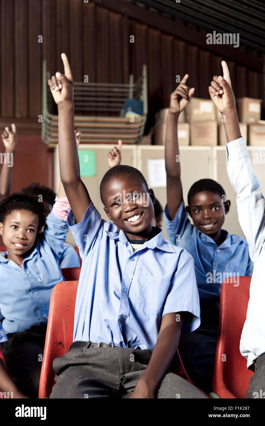 Les élèves de l'école africaine smiling at camera avec leurs mains en l'air Banque D'Images