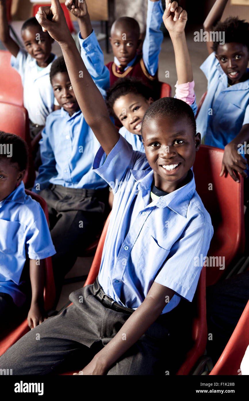 Les élèves de l'école africaine smiling at camera avec leurs mains en l'air Banque D'Images