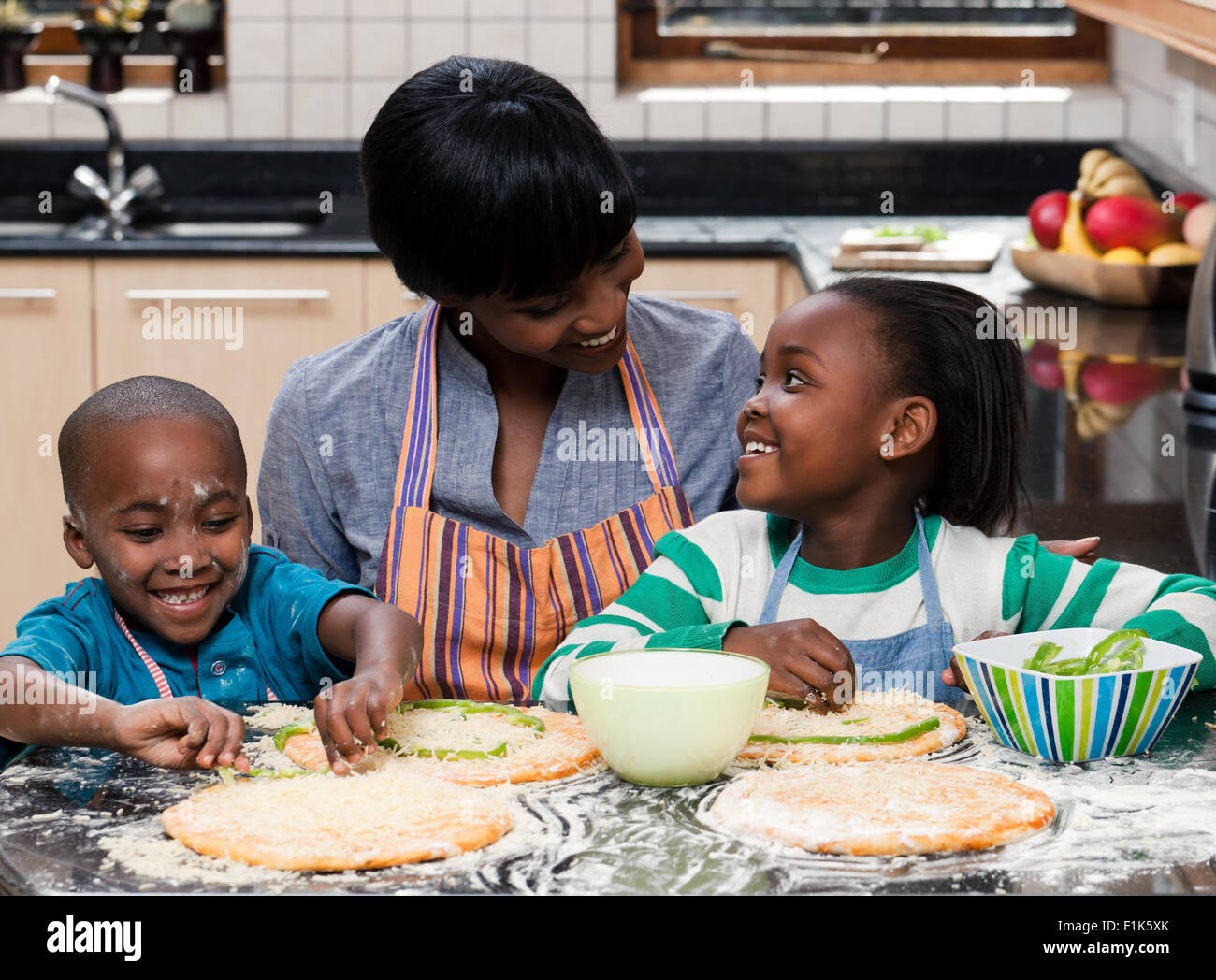 Deux jeunes enfants africains de préparer les aliments avec leur mère Banque D'Images