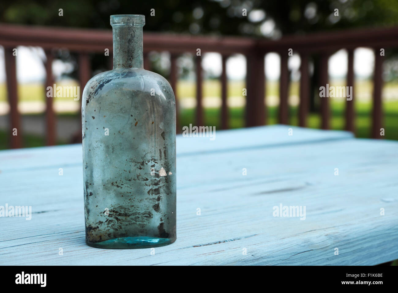 Meubles anciens en verre soufflé, affichée sur un flacon de médicaments peintes en bleu, rustique table de pique-nique. Banque D'Images