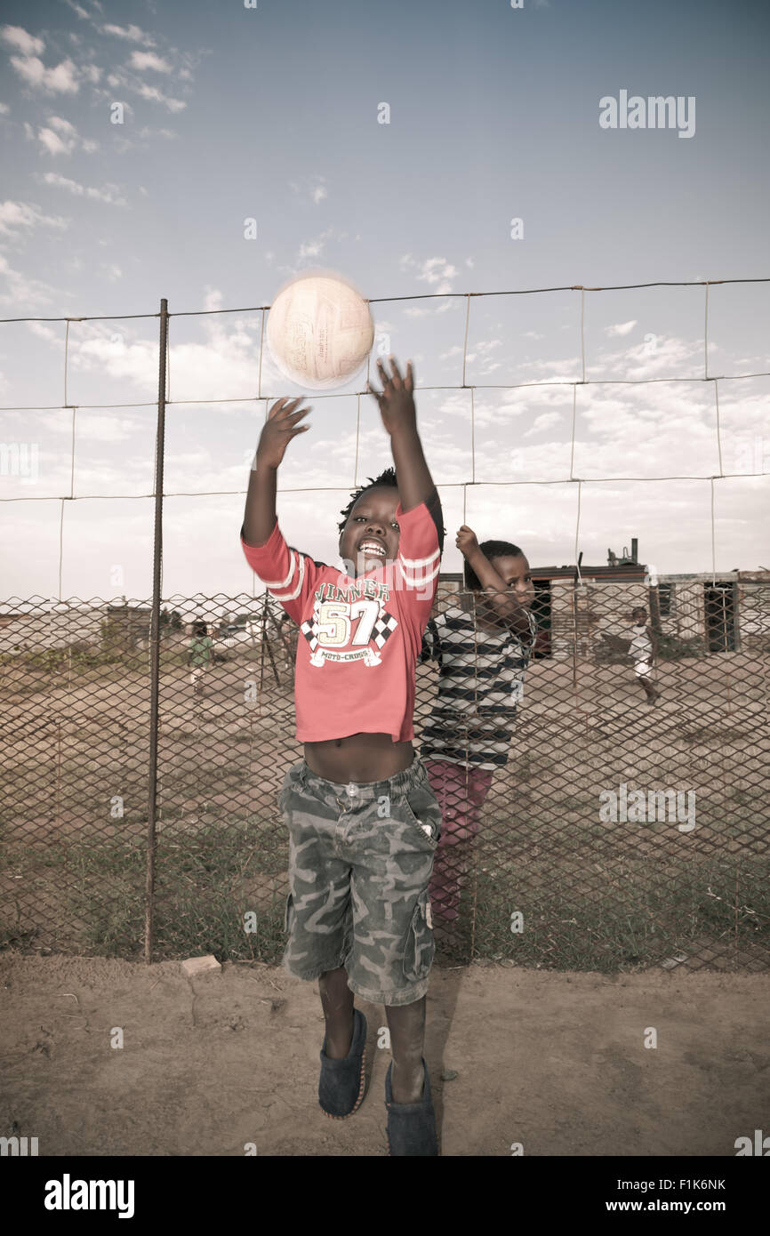 Jeune garçon africain joue avec une balle à l'extérieur Banque D'Images
