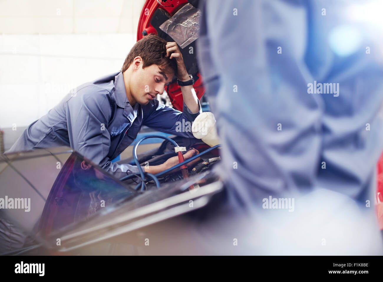 Mécanicien frustrés regardant le moteur en atelier de réparation automobile Banque D'Images