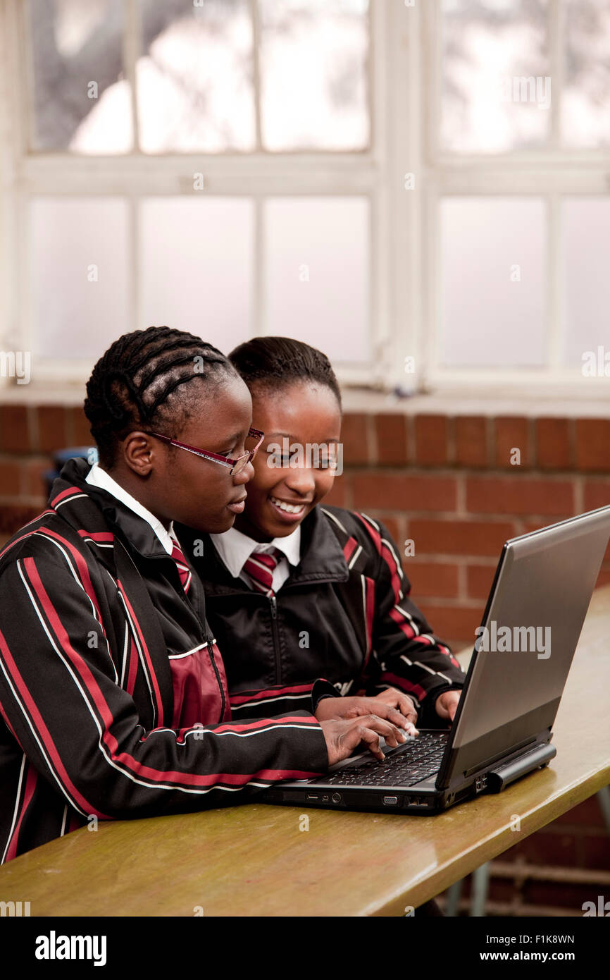 Deux étudiants du secondaire s'asseoir ensemble dans un bureau et travailler sur un ordinateur portable Banque D'Images