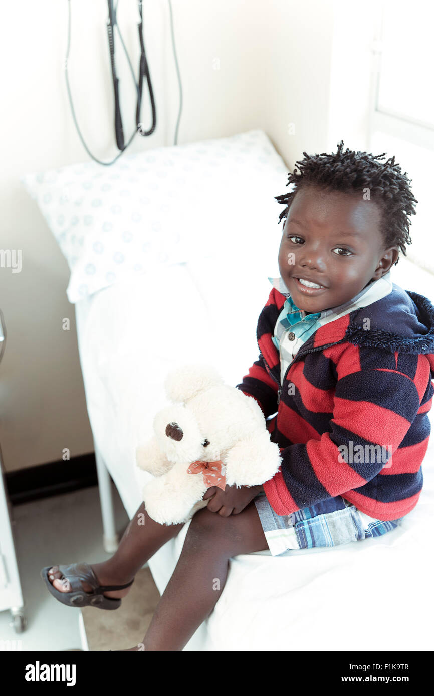 L'Afrique de l'homme enfant assis dans une clinique ward, smiling at camera Banque D'Images