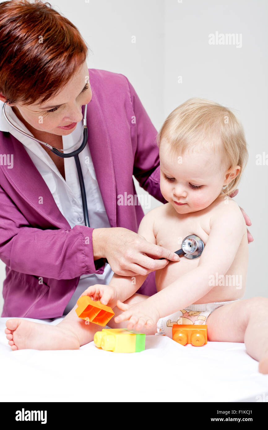 Un pédiatre à l'écoute de la respiration du bébé pendant qu'elle est en cours de lecture Banque D'Images