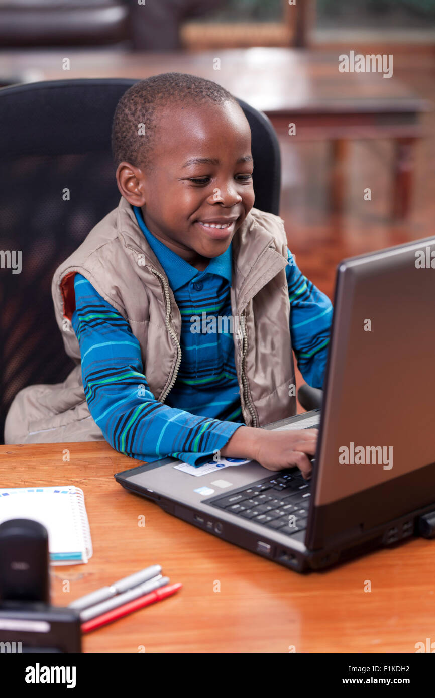Jeune garçon africain assis à son père 24, jouant sur l'ordinateur portable Banque D'Images