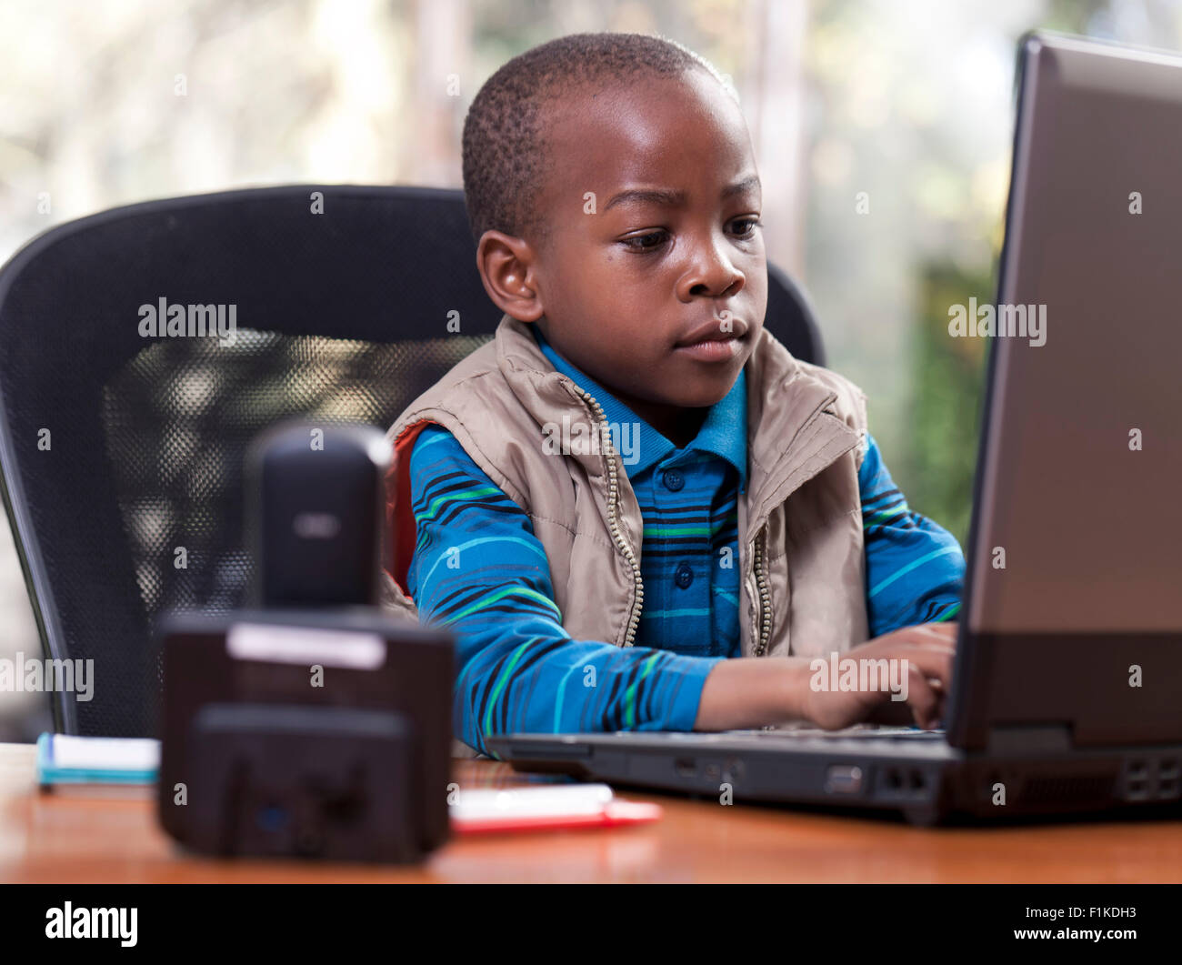 Jeune garçon africain assis à son père 24, jouant sur l'ordinateur portable Banque D'Images