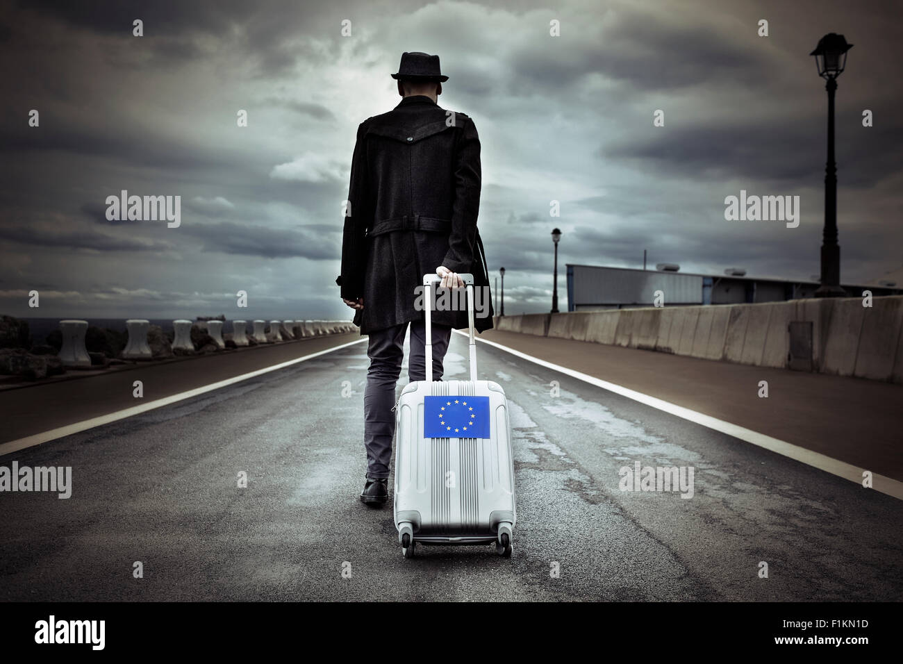 Libre d'un jeune homme vu de dos portant sa valise roulant avec un drapeau européen, avec un effet dramatique Banque D'Images