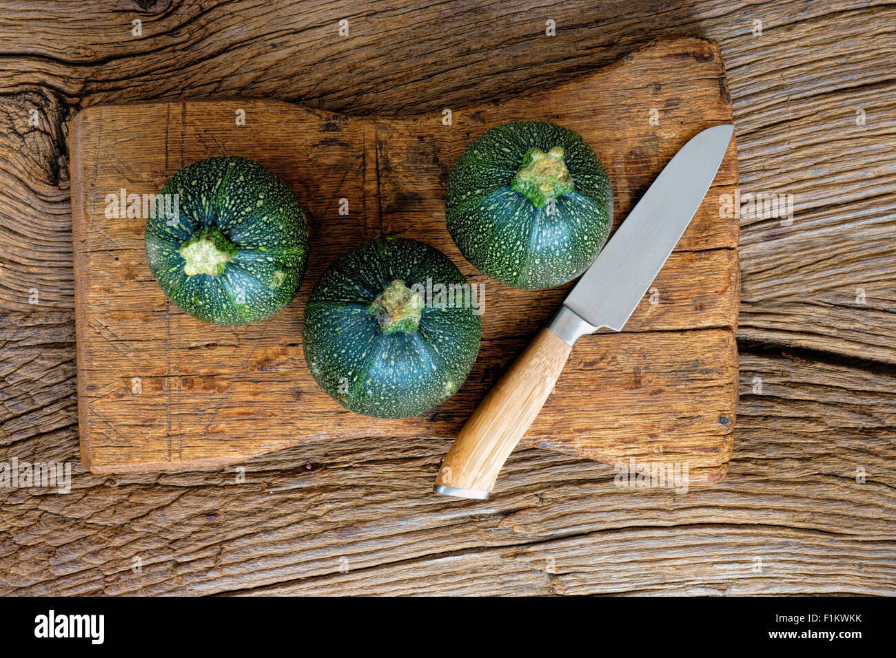 Trois rond et mûr courgettes et un couteau de cuisine, planche à découper en bois rustique sur Banque D'Images