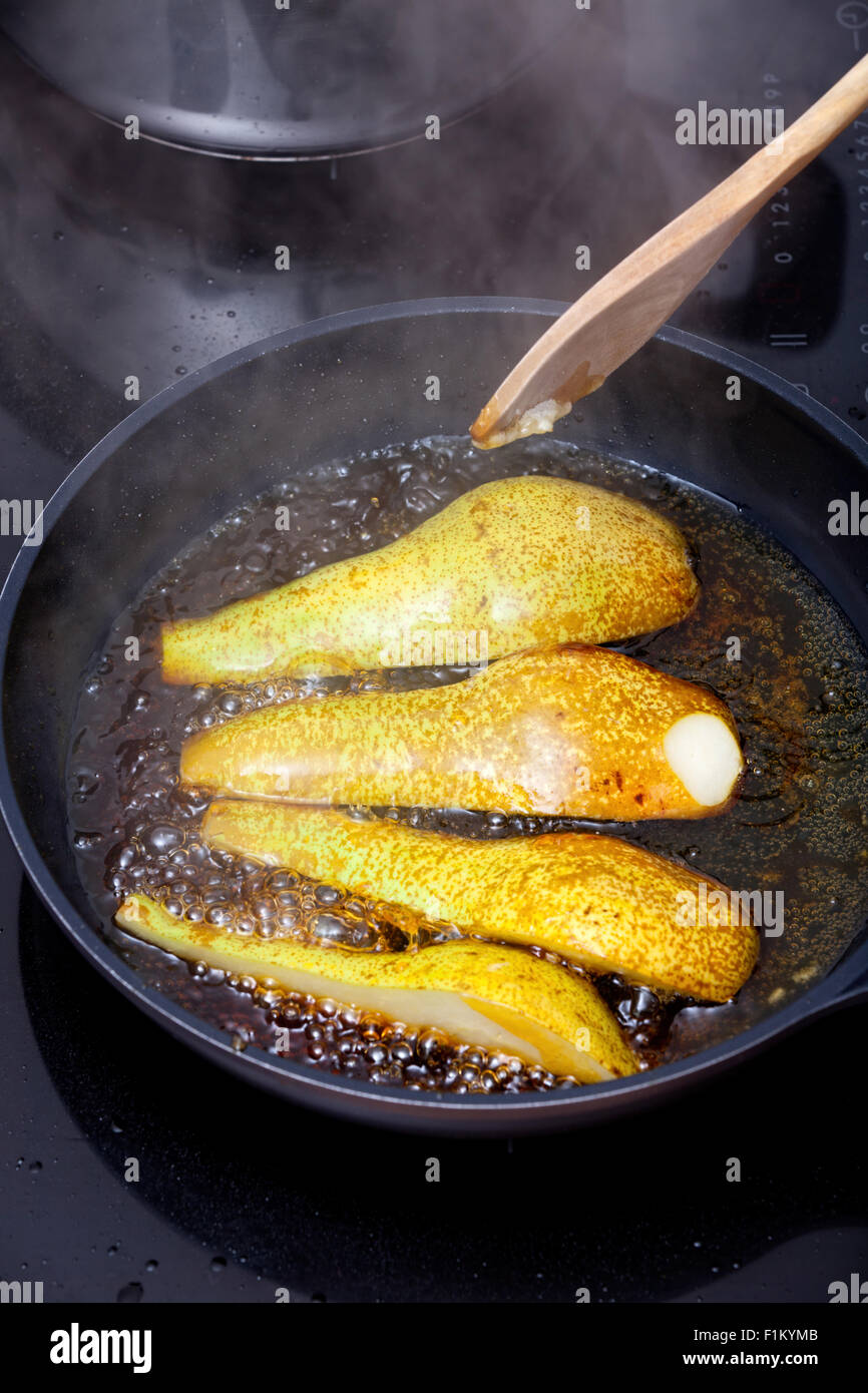 Les poires soient caramélisées Dans une casserole sur la cuisinière avec du sucre Banque D'Images