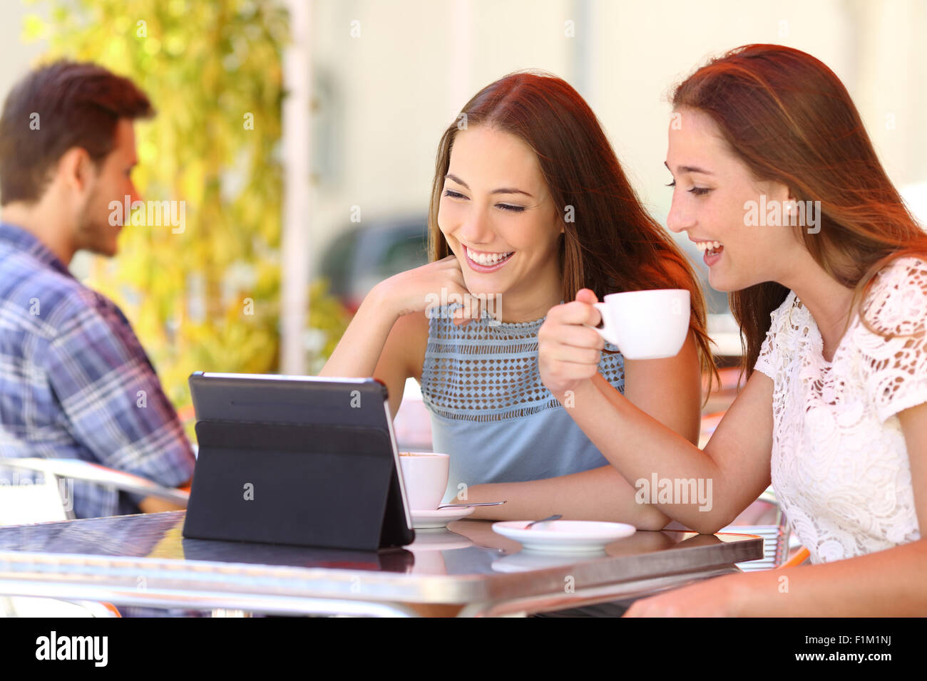 Deux amis ou soeurs de regarder des vidéos dans une tablette dans un café terrasse Banque D'Images