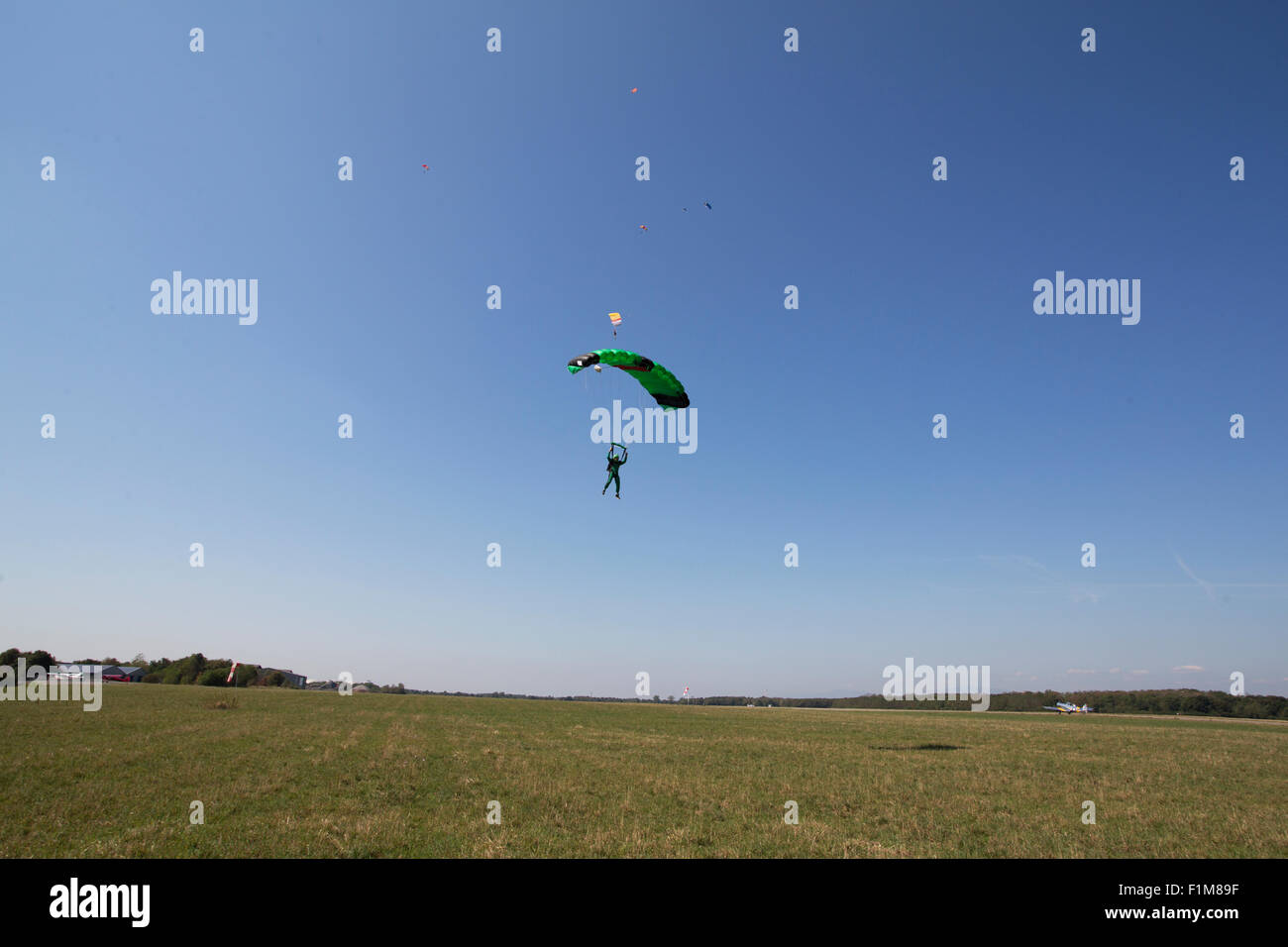 Parachutiste sous voile s'approche de la zone d'atterrissage après une skydive jump dans le ciel bleu. Banque D'Images