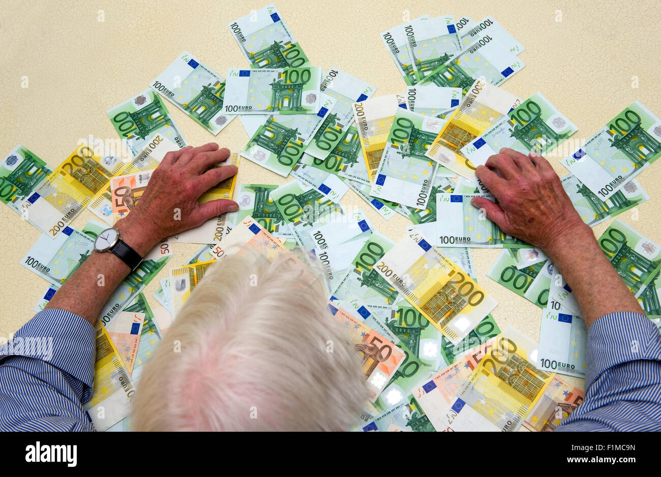 Un homme âgé avec beaucoup de billets sur la table Banque D'Images