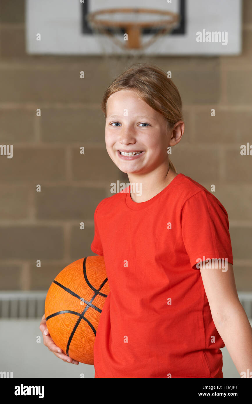 Portrait of Girl Holding Basket-ball au gymnase de l'école Banque D'Images