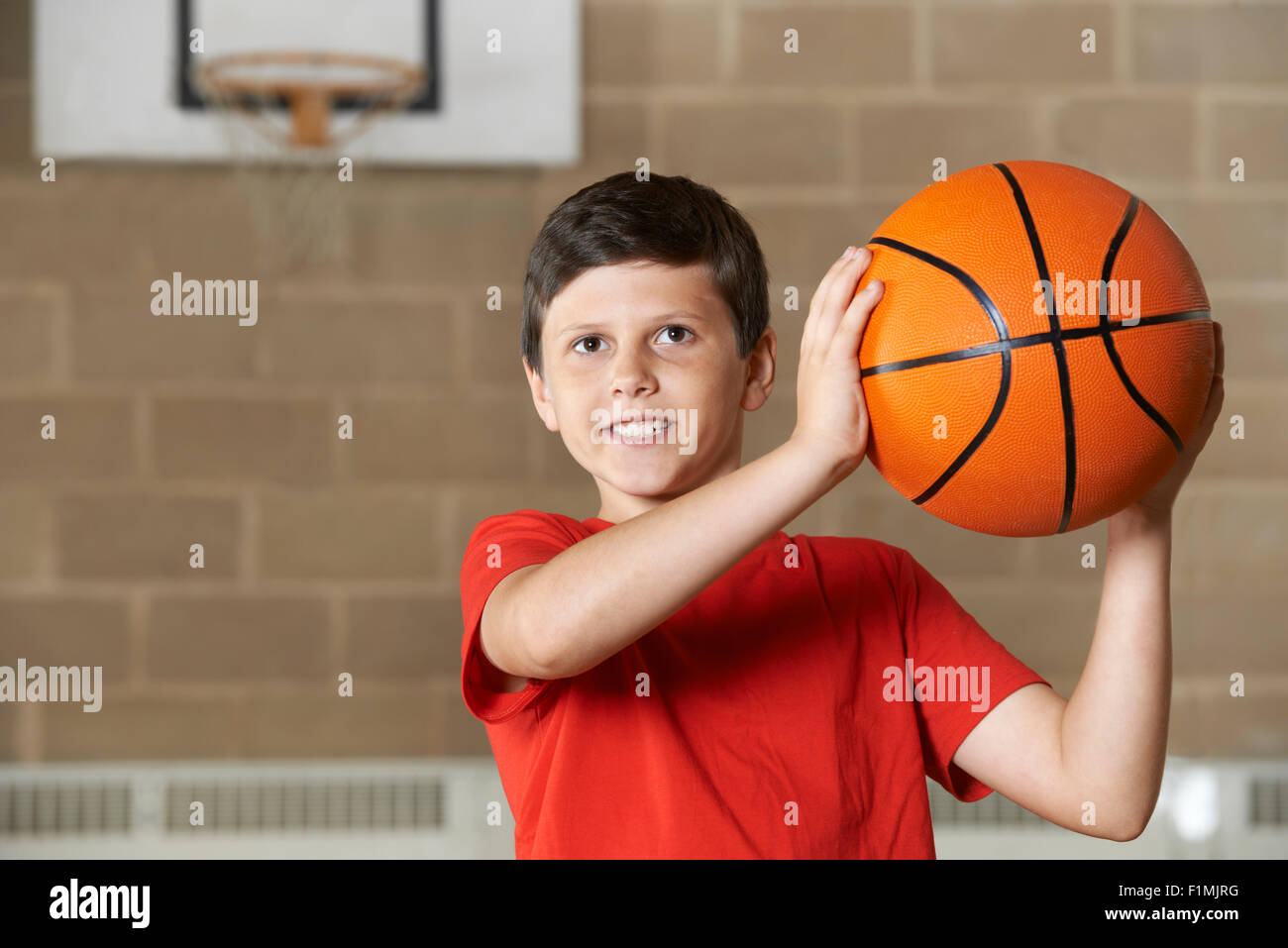 Boy tir pendant match de basket à l'École de sport Banque D'Images