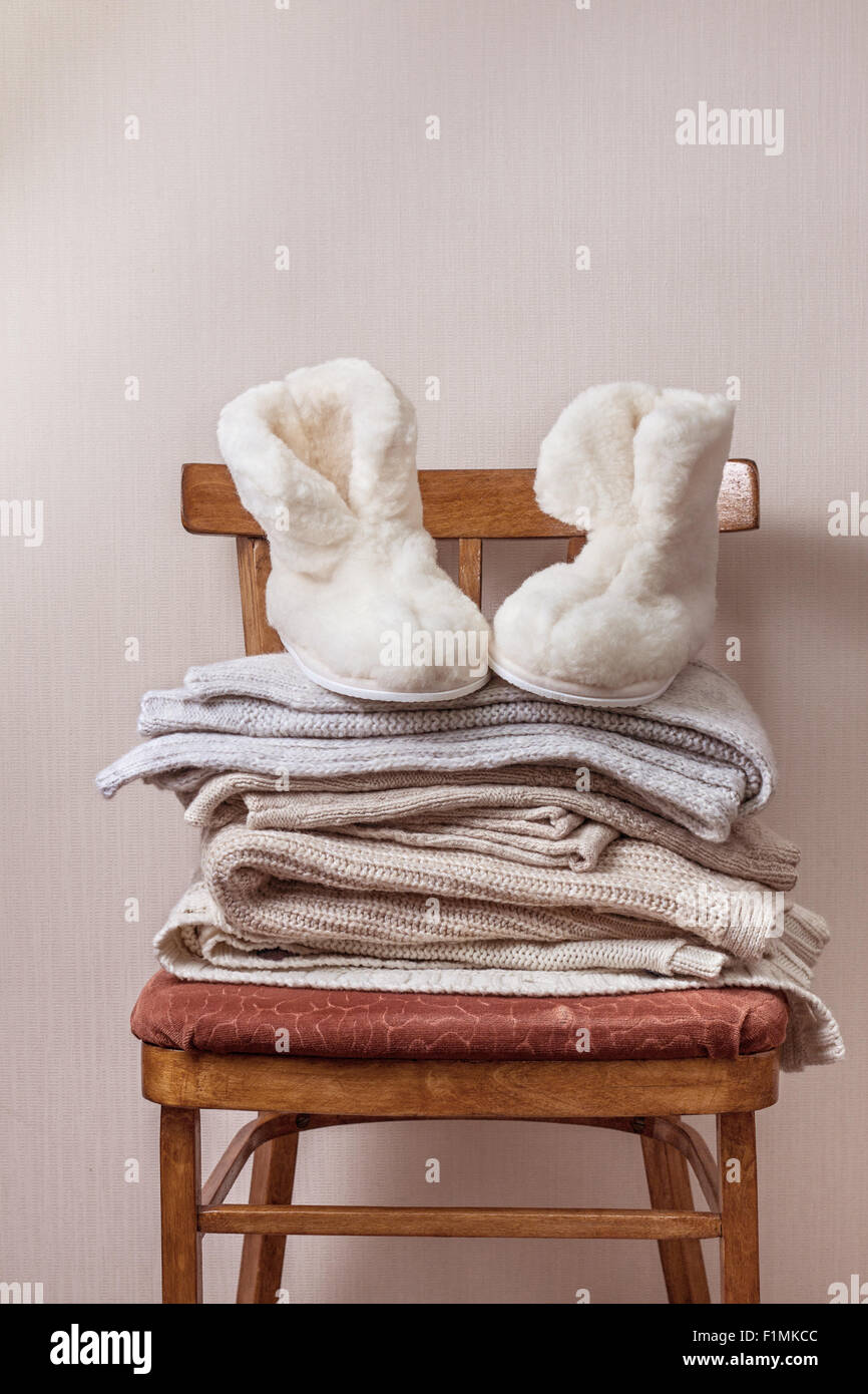 Pile de vêtements chauds sur la chaise, paire de chaussons en peau de mouton d'hiver chaud Banque D'Images