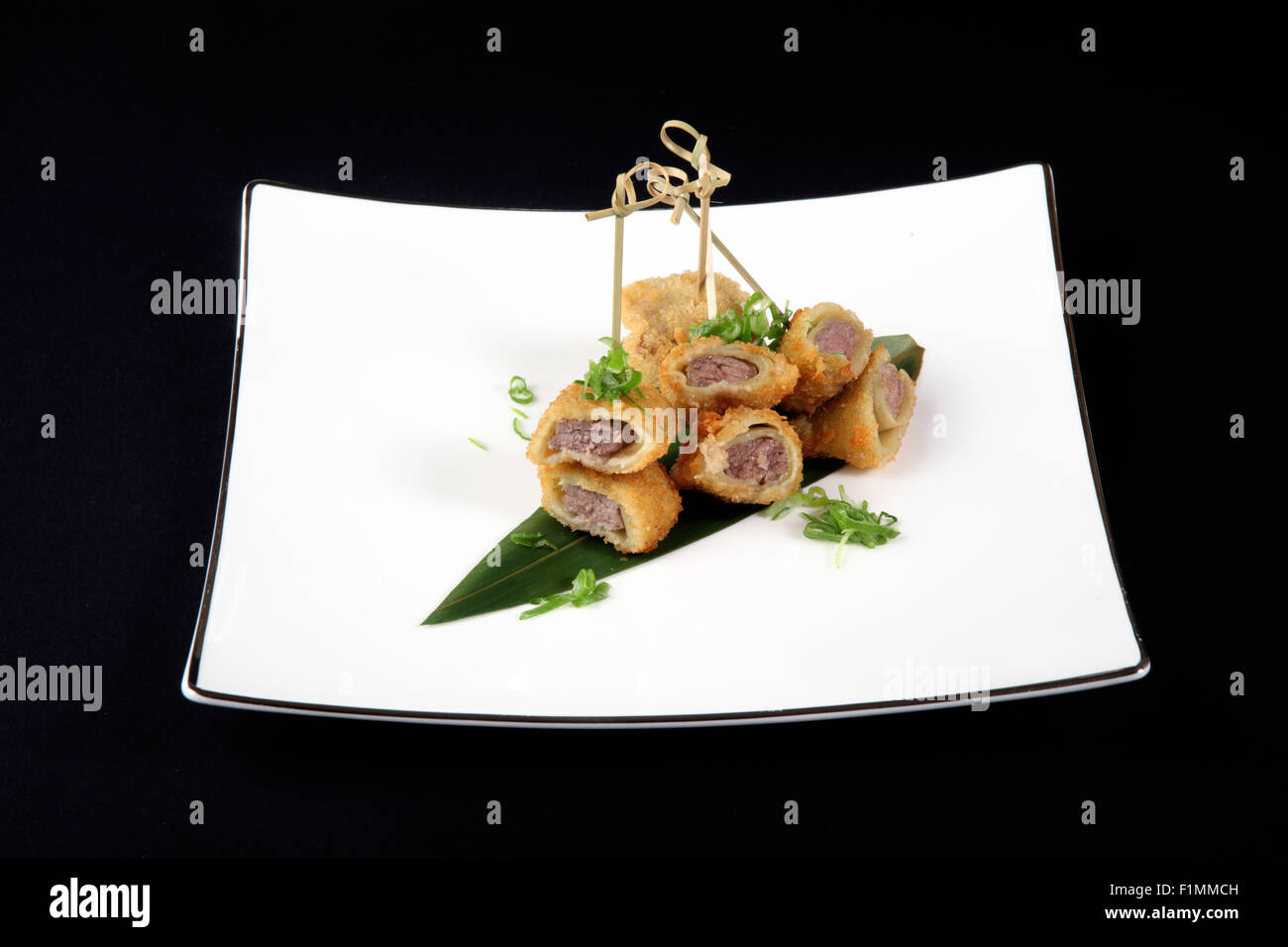 Filets de poisson avec légumes en plaque blanche sur fond noir Banque D'Images