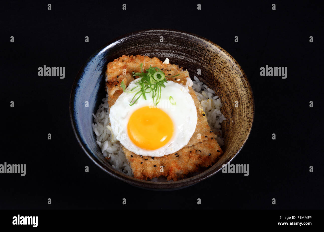 Bol avec du poisson frit, du riz et des oeufs sur un fond noir Banque D'Images