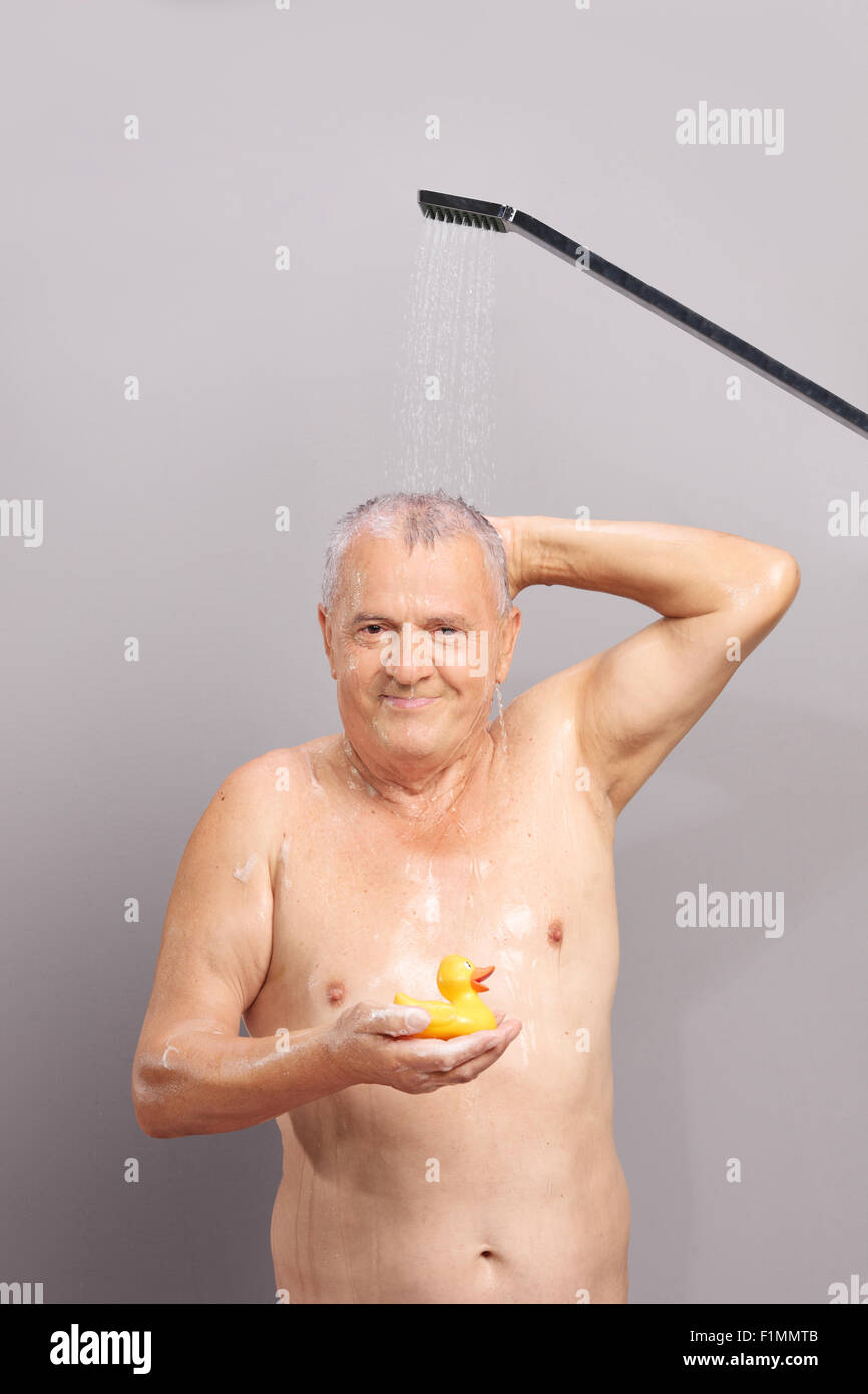 Shot verticale de l'homme de prendre une douche et tenant un canard en caoutchouc jaune Banque D'Images