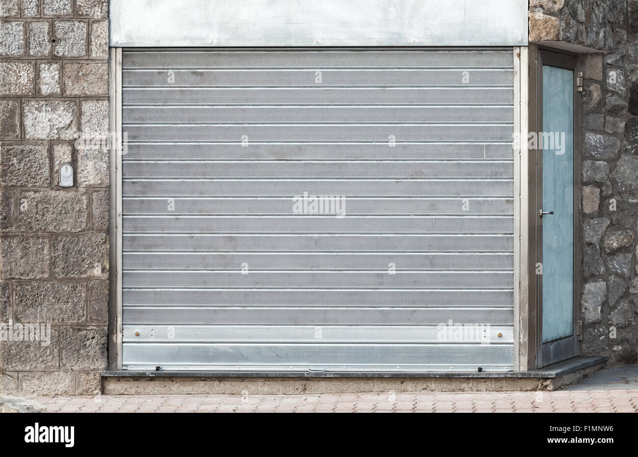 Porte de garage en métal gris dans mur de pierre, la texture d'arrière-plan Banque D'Images