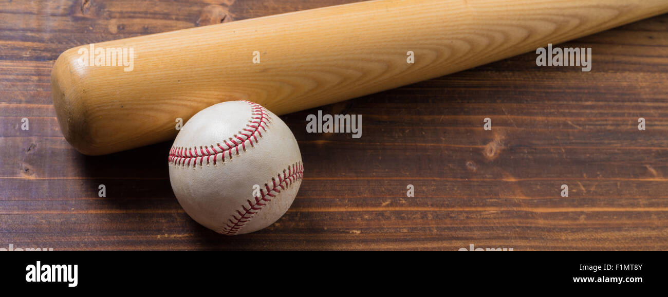 L'équipement de base-ball : batte en bois et balle sur une planche en bois ou un banc arrière-plan Banque D'Images