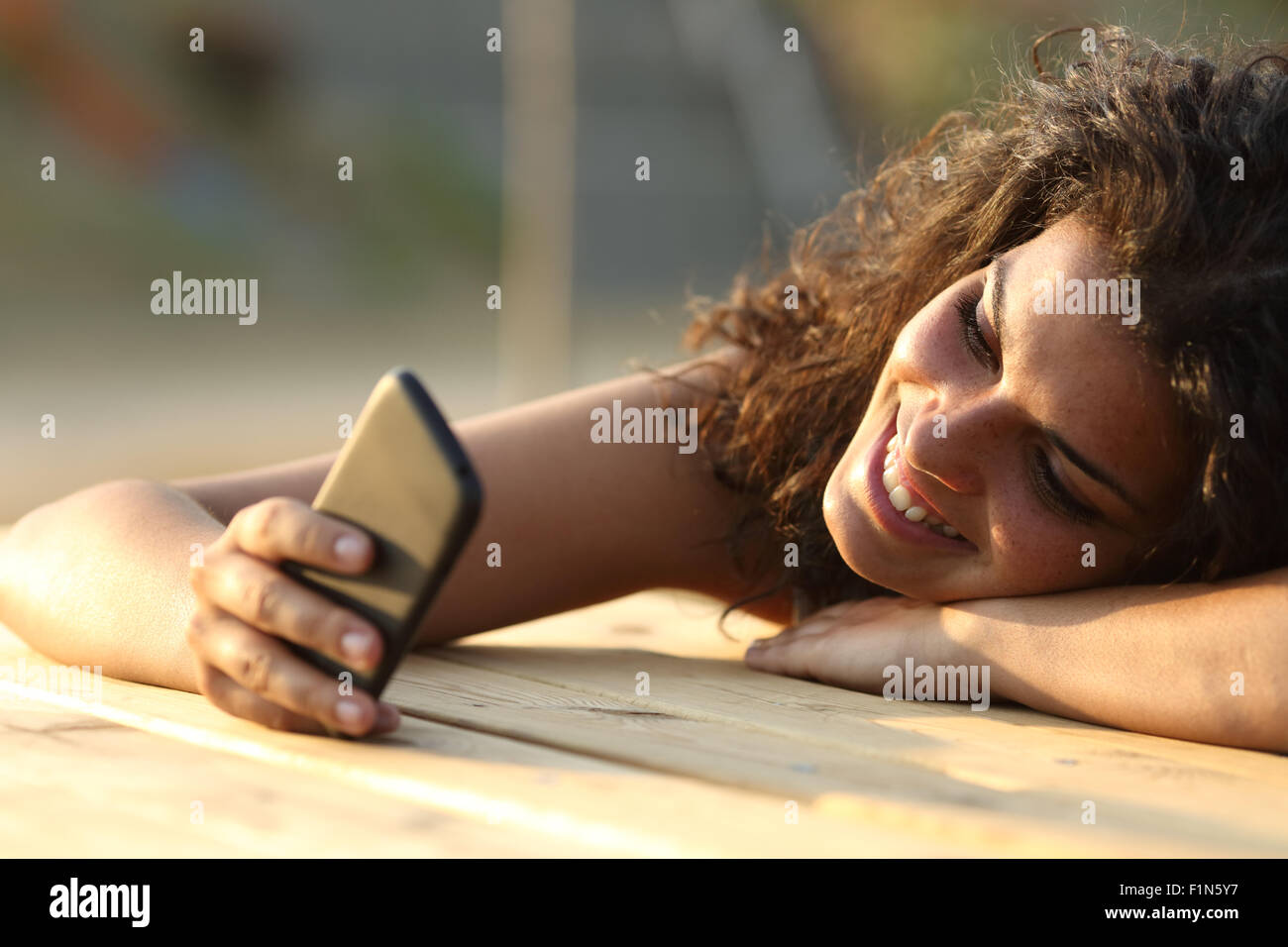 Portrait d'une femme regardant les médias sociaux dans un téléphone intelligent au coucher du soleil dans un parc le tableau Banque D'Images