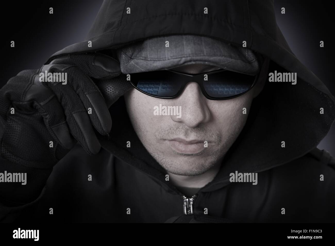 Un hacker en lunettes, gants en cuir noir et le capot face Closeup. Lunettes de soleil en raison de clavier d'ordinateur. Thème cyber-attaque. Banque D'Images