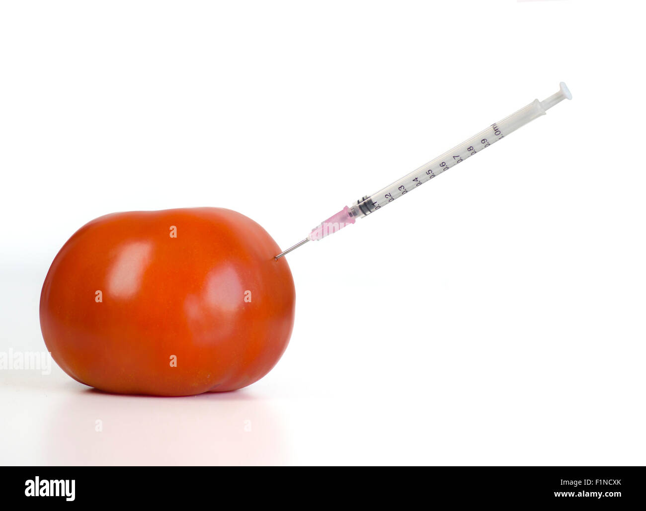 Organisme génétiquement modifié food concept image. Seringue à aiguille injectés à l'intérieur de la tomate Banque D'Images
