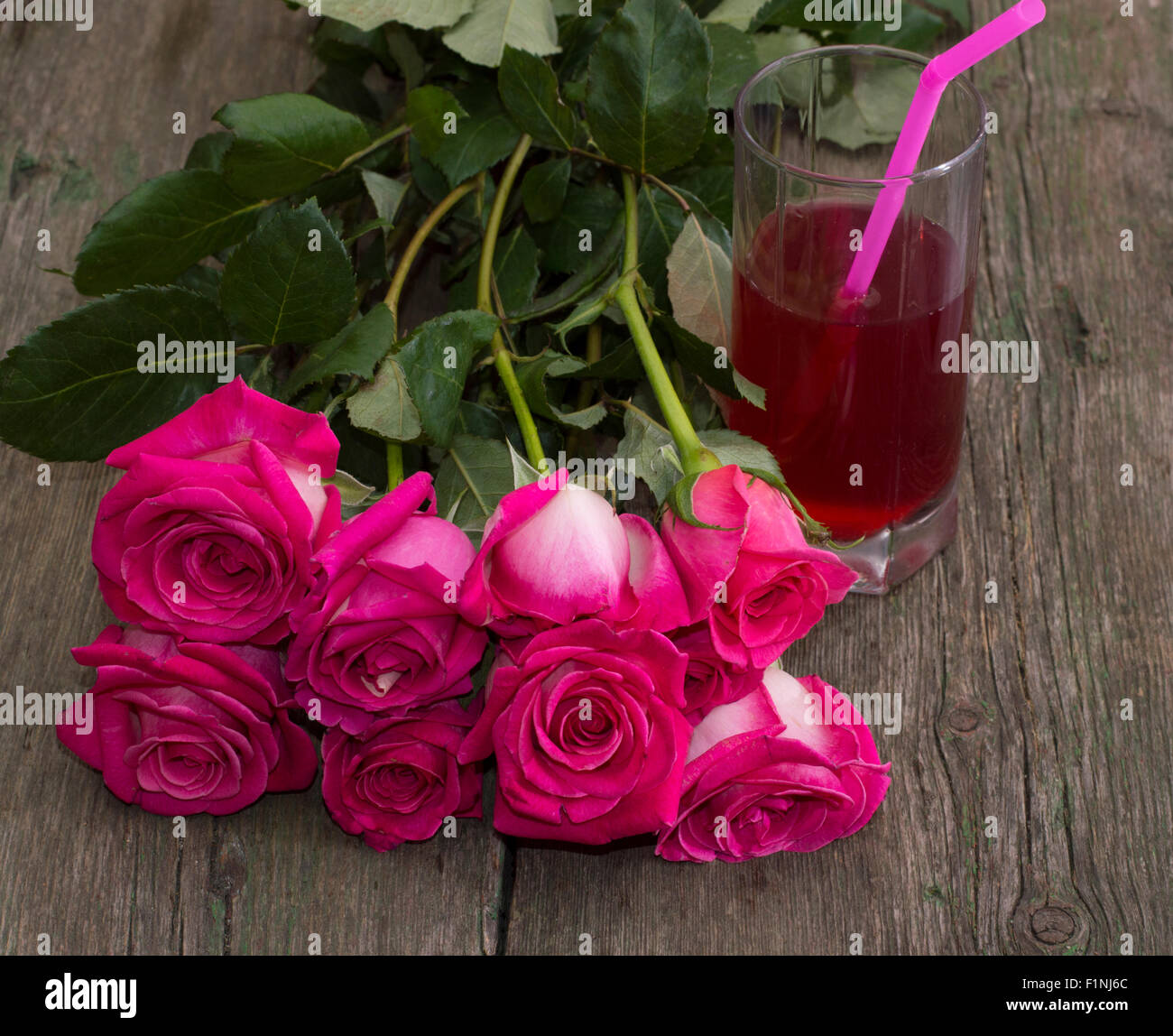 Bouquet de roses rouges et verre de jus avec un tube distal Banque D'Images