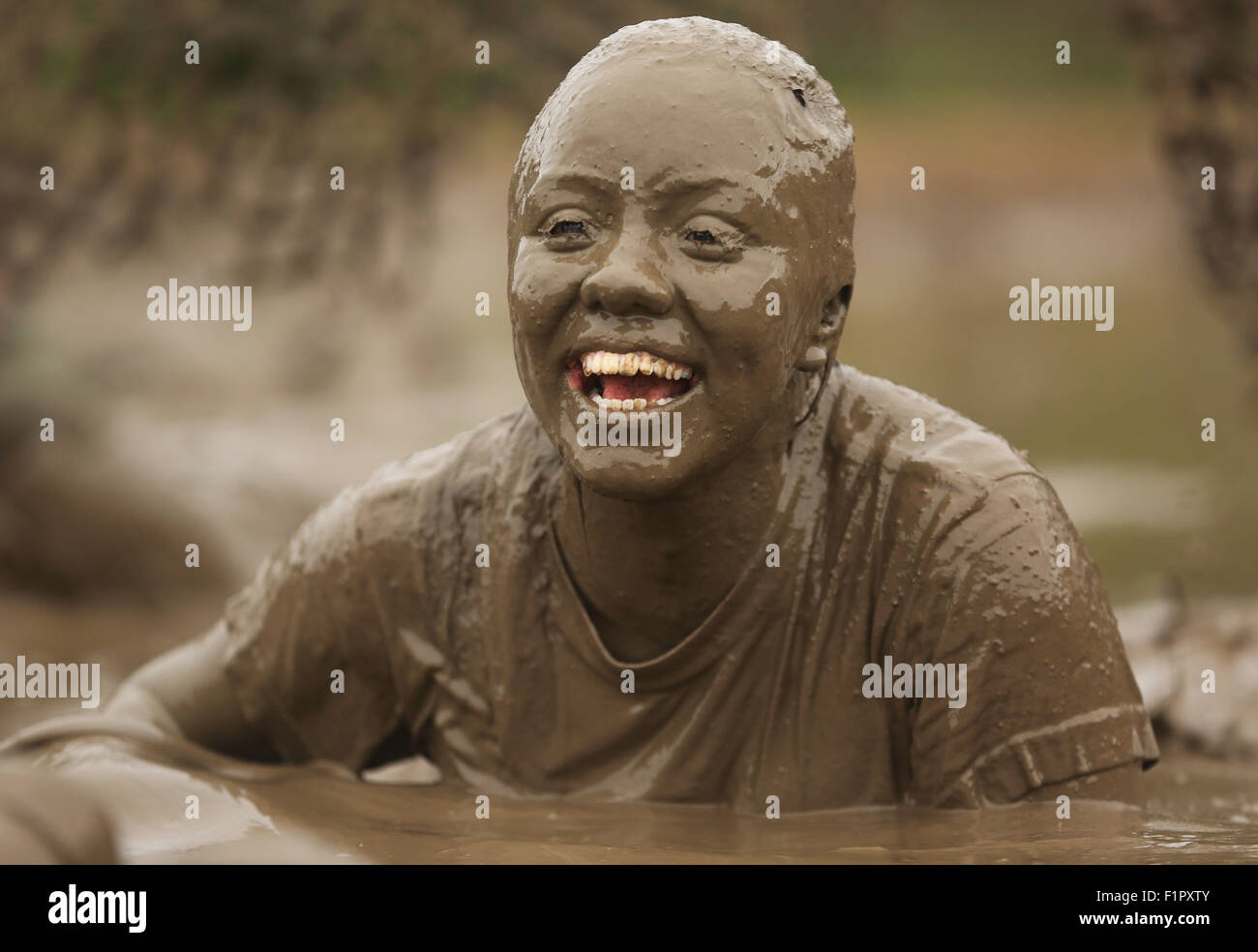 Une femme U.S. Marine couvert de boue pendant le général commandant's Cup Mud Run de Camp Pendleton, 12 juin 2015 à Oceanside, en Californie. La Mud Run est une course à travers la boue des fosses, des pentes glissantes et nageant à travers la boue épaisse à la ligne d'arrivée. Banque D'Images