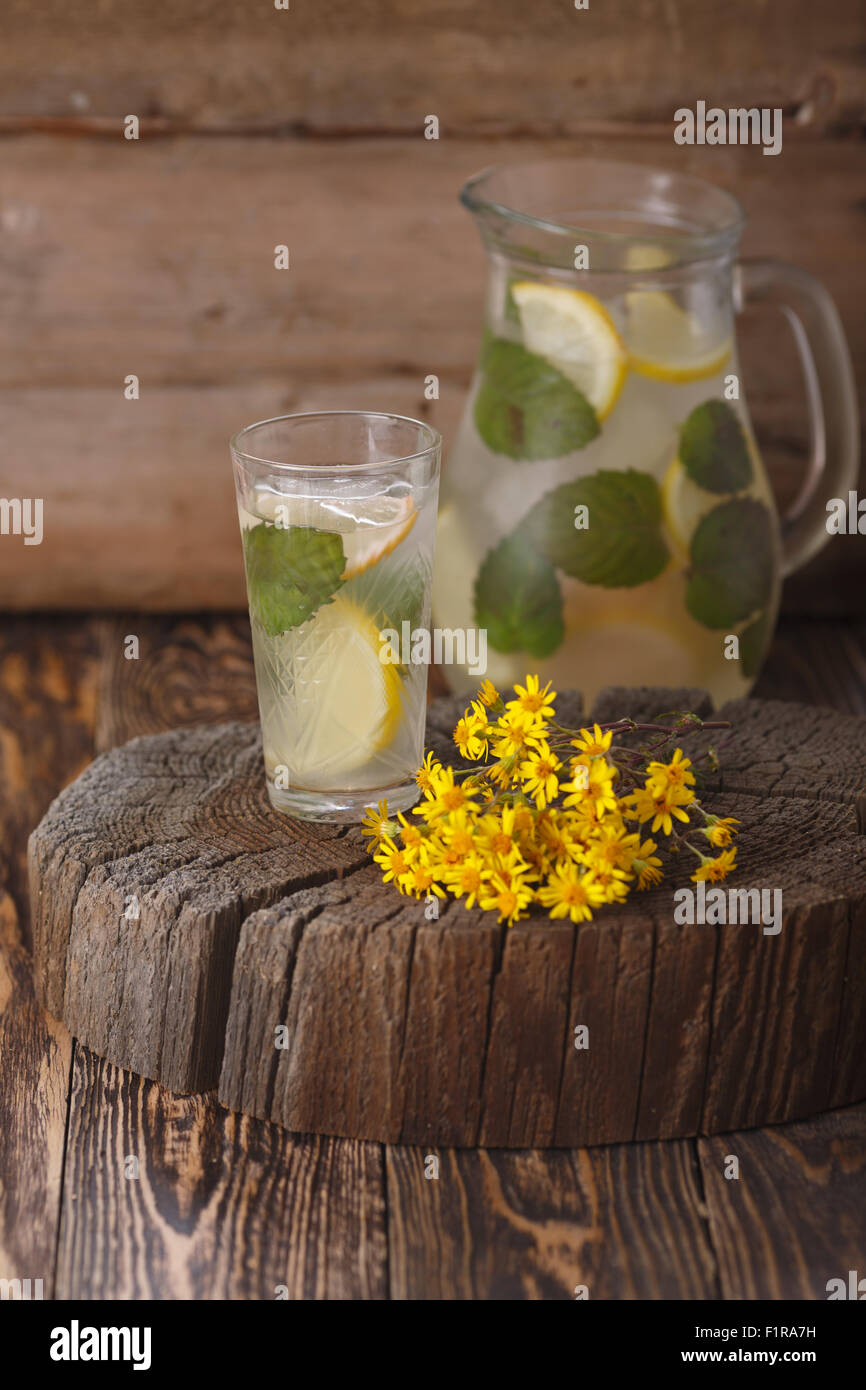 Pichet de limonade à la menthe sur une table en bois près de yellow fleurs sauvages Banque D'Images