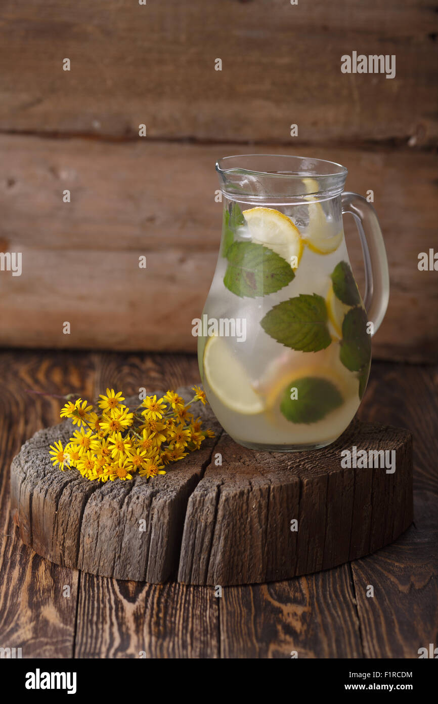 Pichet de limonade à la menthe sur une table en bois près de yellow fleurs sauvages Banque D'Images