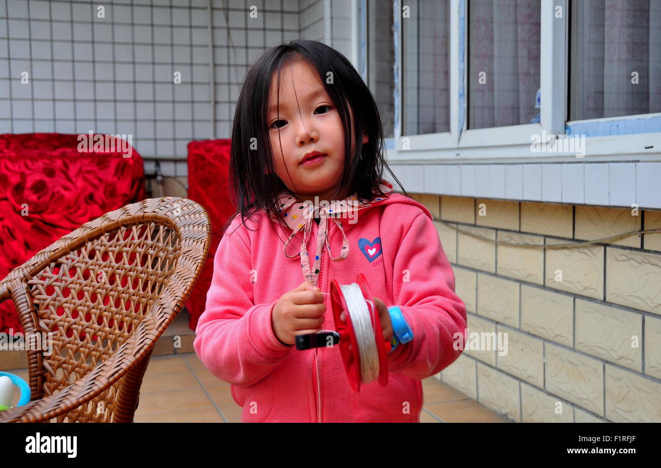 Pengzhou, Chine : douce petite fille chinoise jouant avec une bobine de pêche Banque D'Images